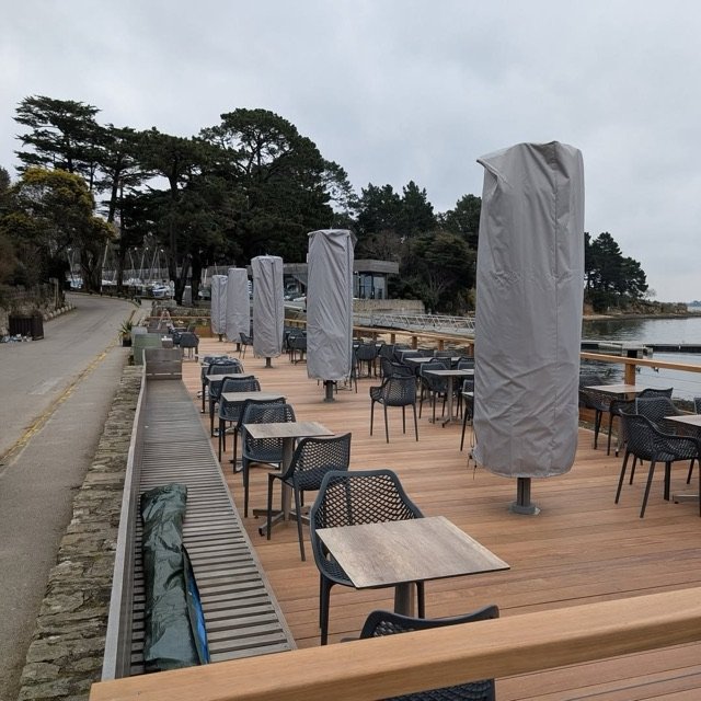 Parasols Prostor repliés sur la terrasse en bois d'un restaurant à Arradon