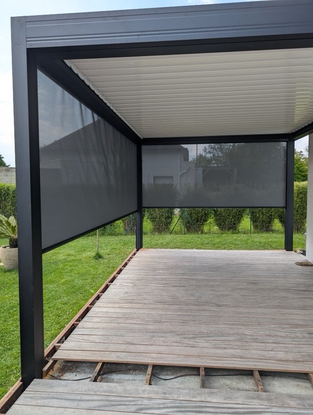 Stores zip descendus à mi-hauteur sur les côtés d'une pergola bioclimatique
