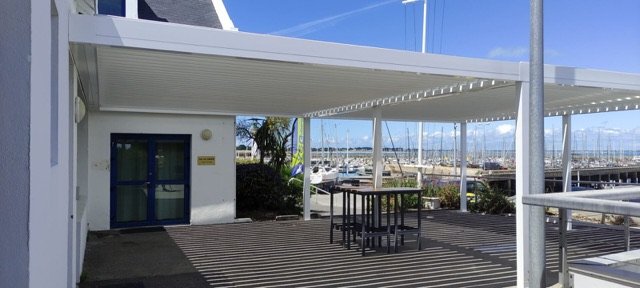 Grande pergola bioclimatique blanche couvrant la terrasse d'un club nautique à Quiberon