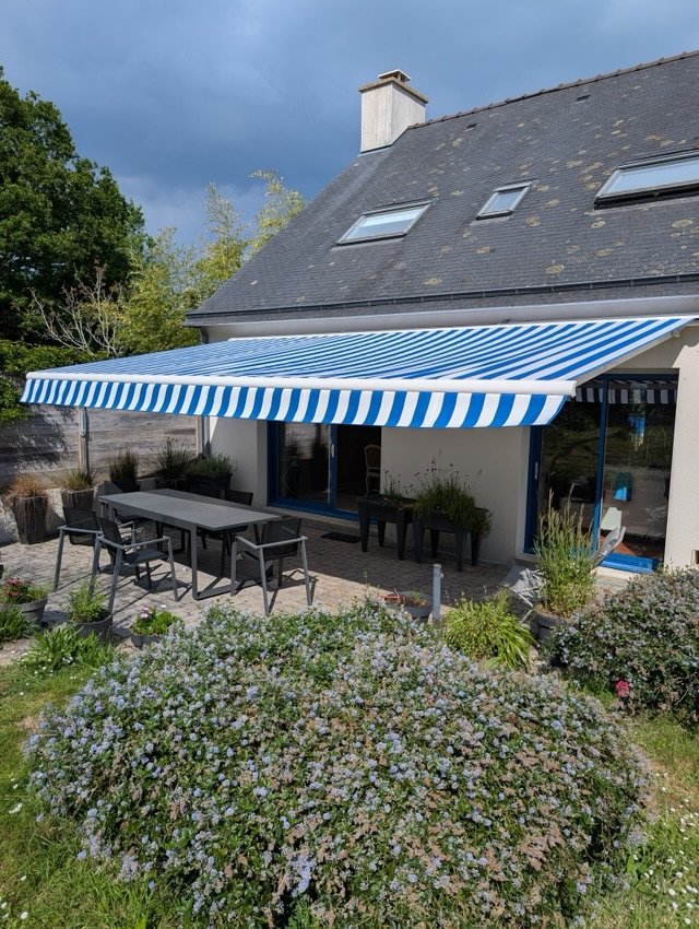Store banne à toile rayée bleu et blanc déployé sur une terrasse à Sarzeau